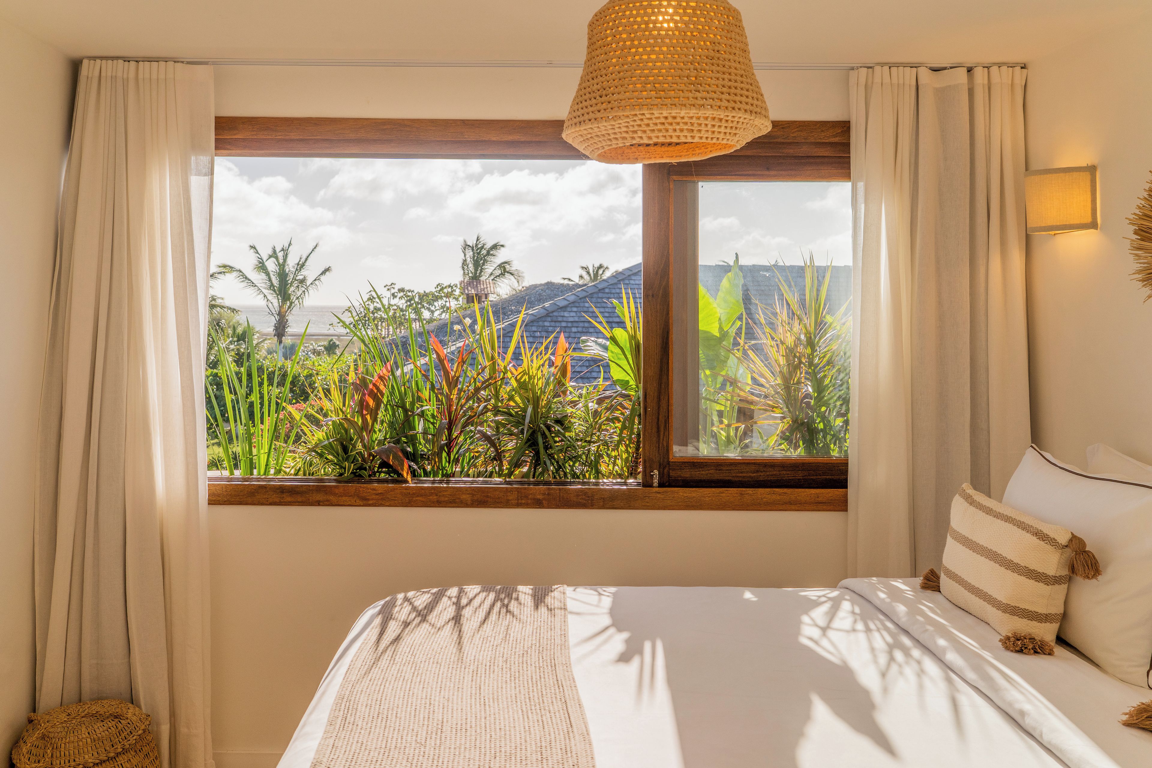 A bedroom with a large window, a bed, and a hanging light fixture.