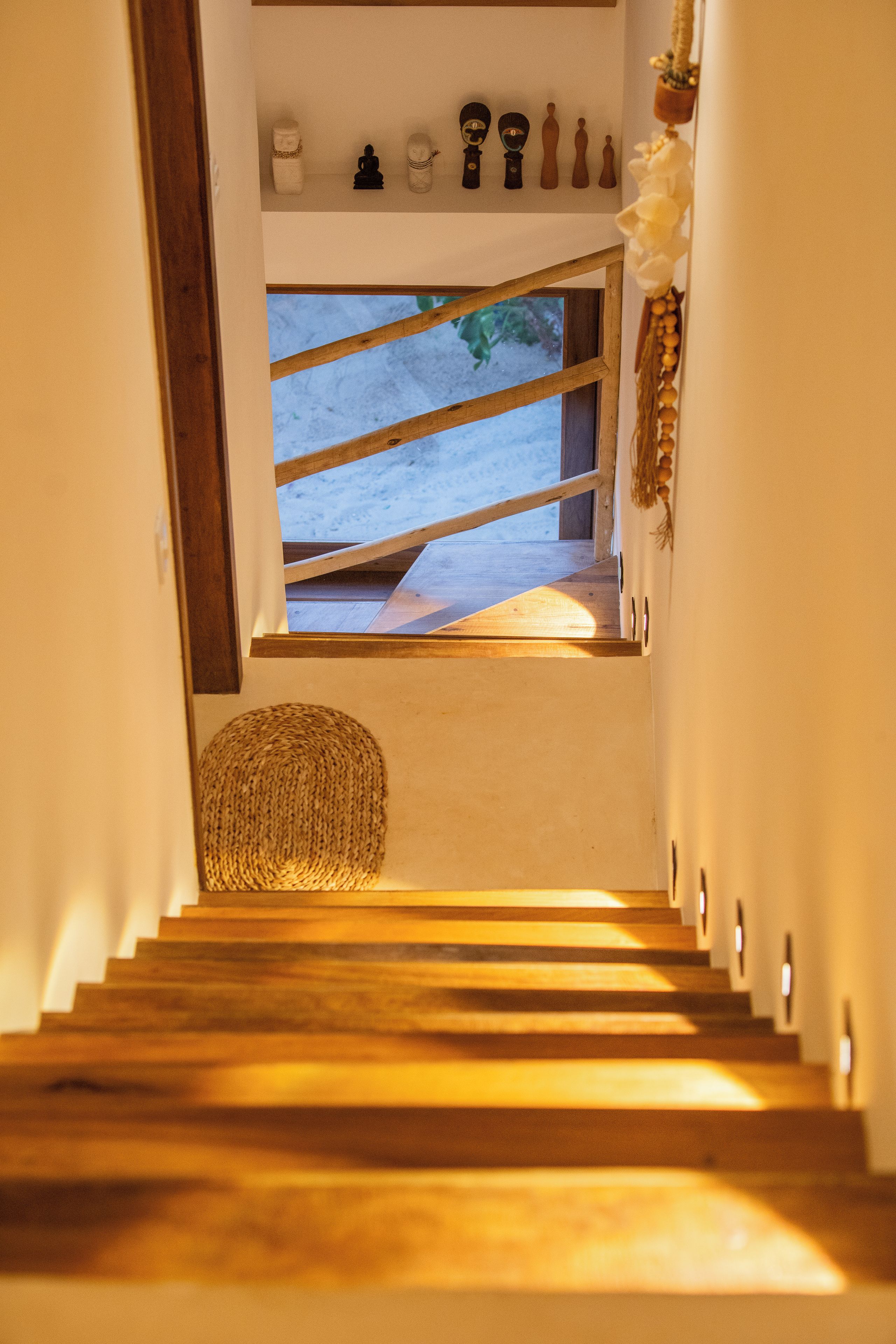 A wooden staircase leading to a window with a view of snow-covered ground.