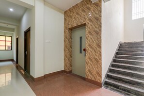 Ein Korridor mit Marmorboden, einer Holztür und einer Treppe mit einer Marmorhandläufer.