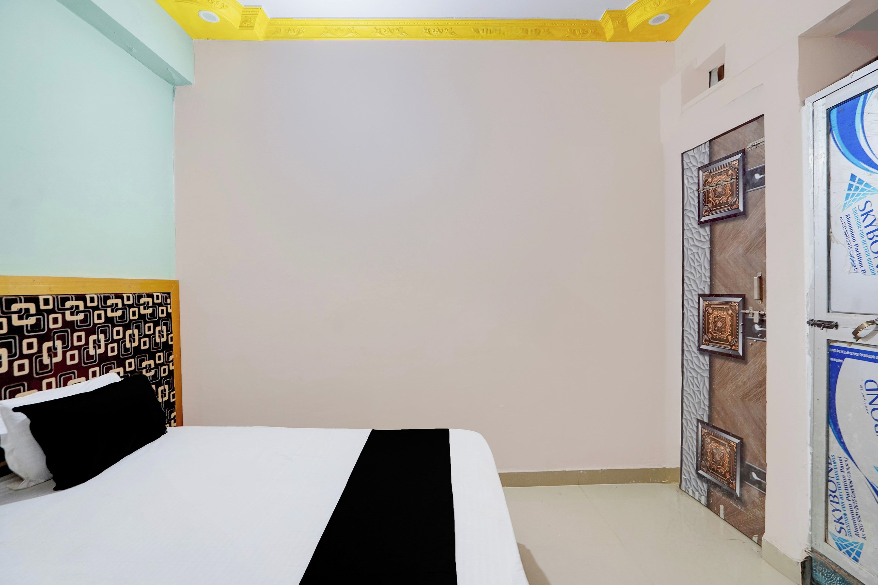 A hotel room with a bed, a door with decorative panels, and a patterned wall.