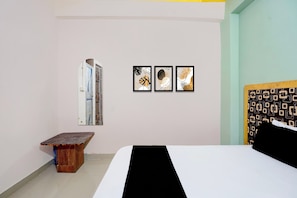 A bedroom with a bed, a wooden bench, and three framed artworks on the wall. - Hotel O Swarn kamal Inn (Patna)