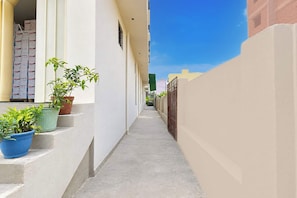 A narrow corridor with steps leading to a building entrance, potted plants, and a clear sky. - Hotel O Swarn kamal Inn (Patna)
