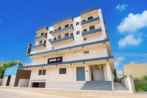 Un hotel de varios pisos con fachada plana, balcones en cada planta y un cartel que indica que es el Hotel OYO Swarn Kamal Inn.