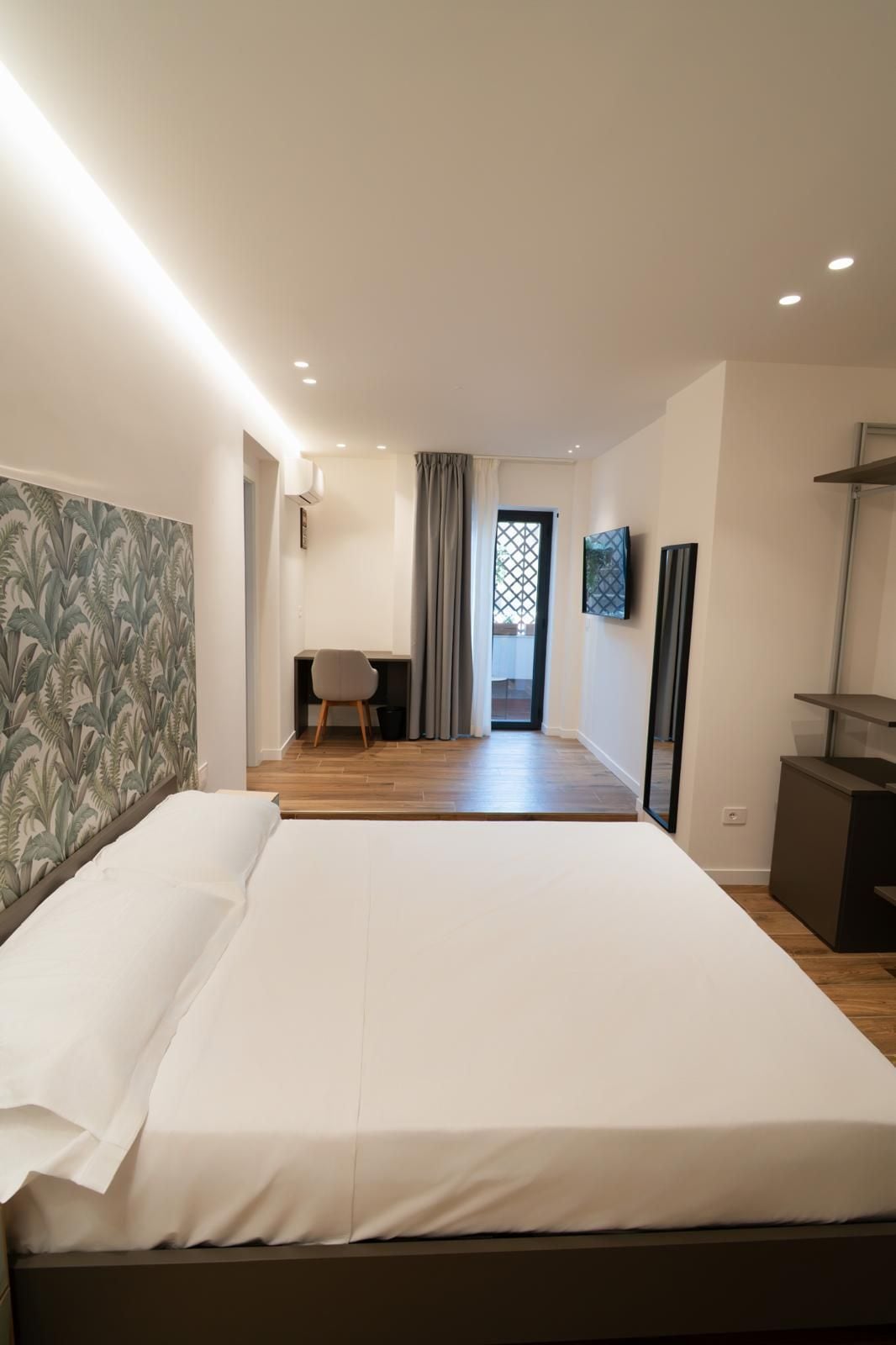 Een moderne slaapkamer met een groot bed, een bureau en een stoel.