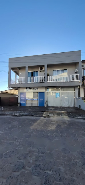 Ein zweistöckiges Gebäude mit einem Balkon, einer blauen Tür und einem Schild mit der Aufschrift 'DLCOR'.