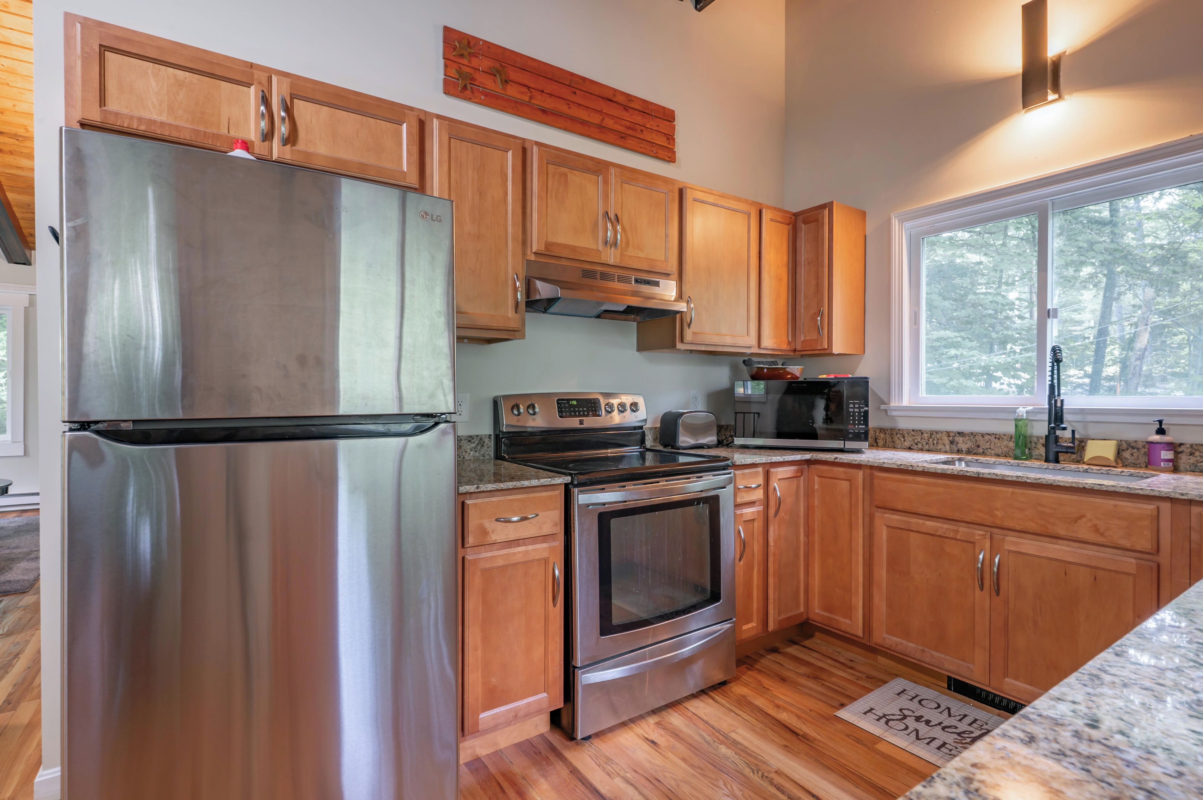 A modern kitchen with stainless steel appliances, wooden cabinets, and a granite countertop.