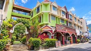 A multi-story building with a green facade, a red entrance, and a balcony with railings. - Central Patong Beach Resort (Kathu)