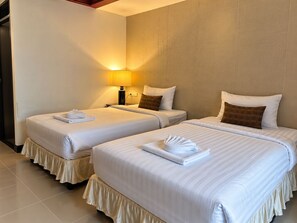 A hotel room with two beds, each with a white bedspread and pillows, and a bedside table with a lamp. - Central Patong Beach Resort (Kathu)
