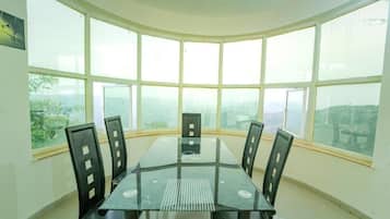 A conference room with a glass table and black chairs, large windows with a view of the city, and a white ceiling.