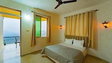 A bedroom with a bed, a ceiling fan, two wall-mounted lights, a window with curtains, and a view of the outdoors.