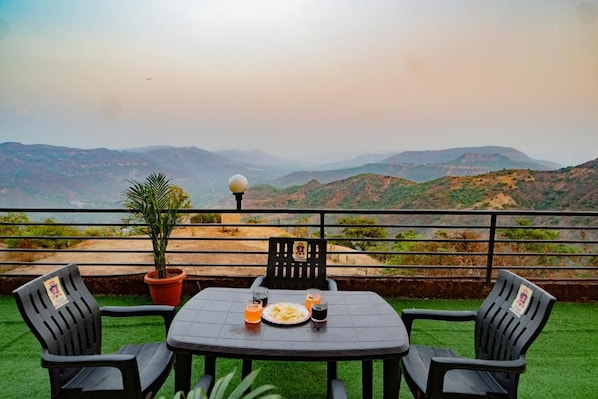 Une table avec des chaises et un pot de fleurs sur une terrasse offrant une vue sur les montagnes.
