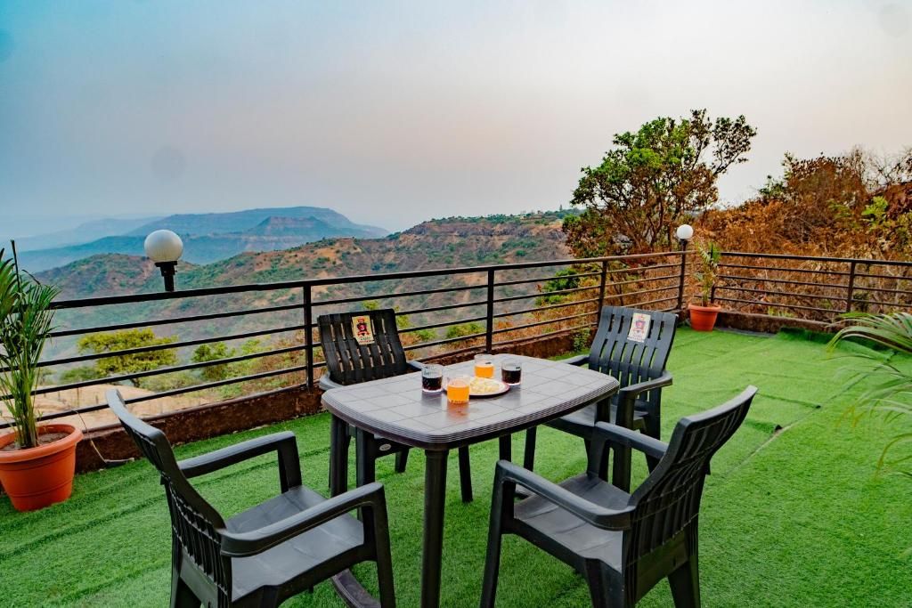 A terrace with a table and chairs, potted plants, and a view of the hills.