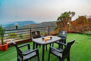 Une terrasse avec une table et des chaises, des plantes en pot et une vue sur les collines.