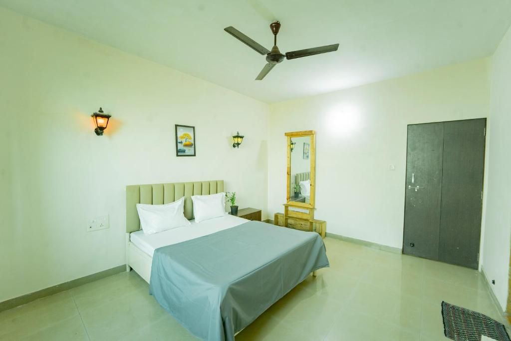 A bedroom with a bed, a ceiling fan, a nightstand, a mirror, and a wardrobe.