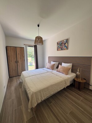 Une chambre à coucher avec un grand lit, une armoire, une table de chevet et un luminaire suspendu.
