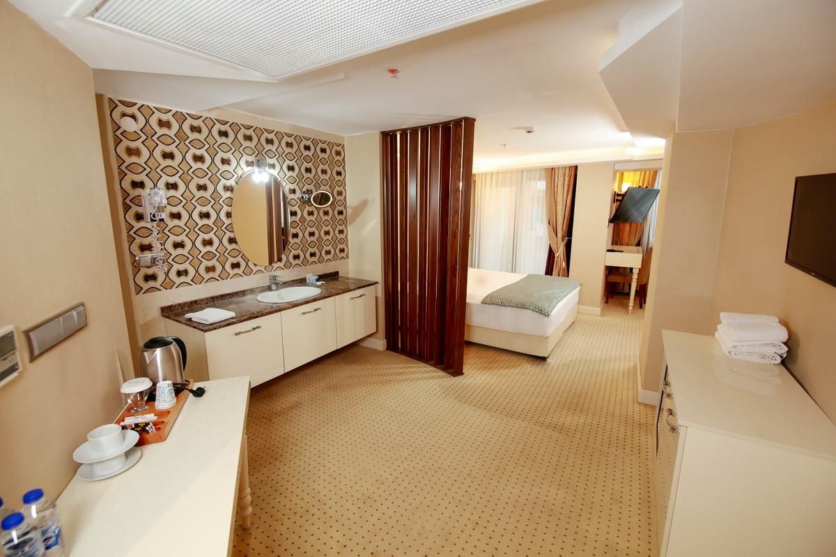 A hotel room with a bed, a bathroom with a sink and mirror, and a breakfast tray on the counter.