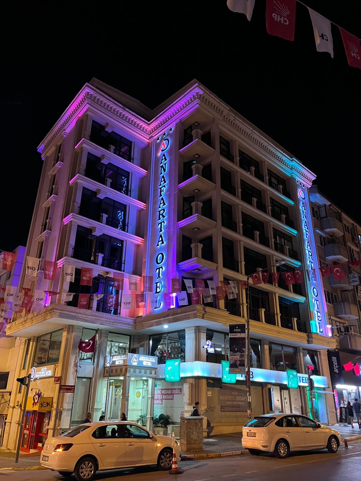 A hotel with multiple floors, a prominent neon sign, and flags.