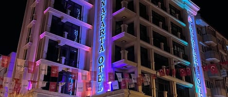 Un hotel con varios pisos, un llamativo letrero de neón y banderas.