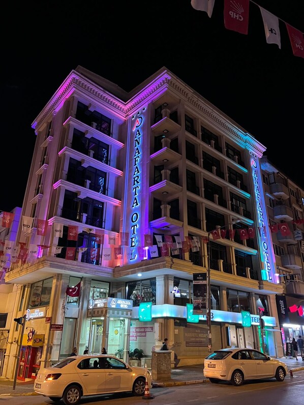 Un hotel con varios pisos, un llamativo letrero de neón y banderas.