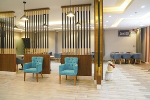 A hotel lobby with seating areas, a reception desk, and a wall with Arabic calligraphy. - Ferbion Hotel Almajardah (An Nimas)