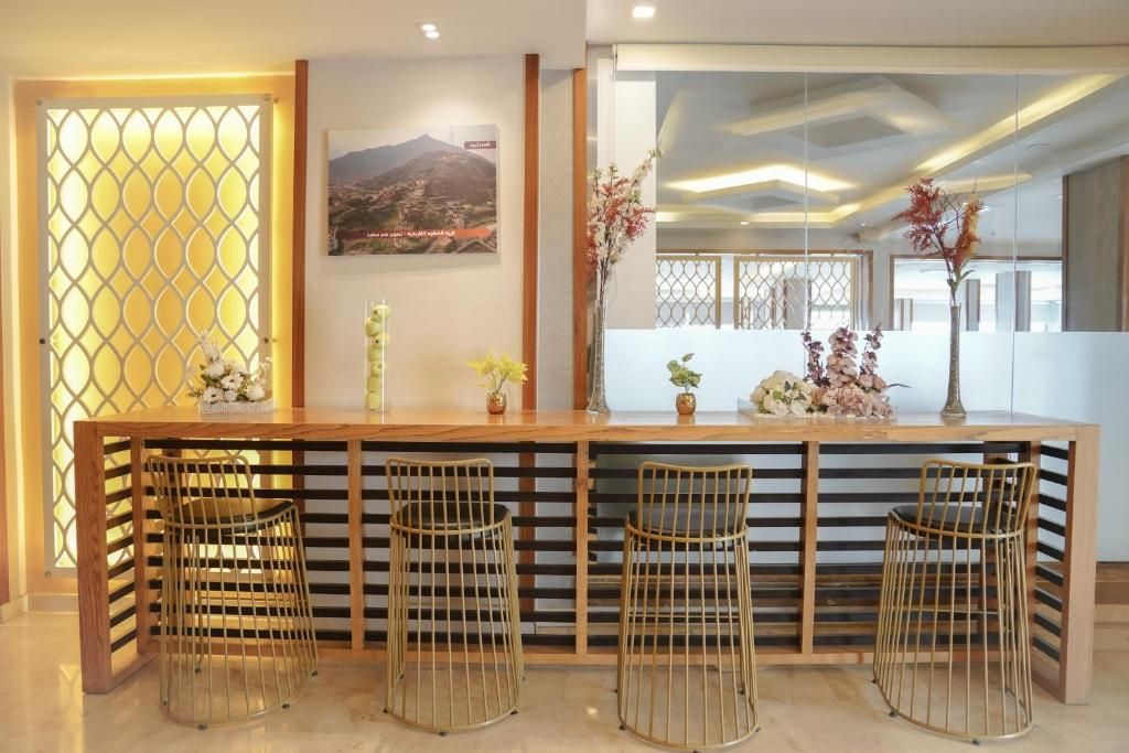 A reception area with a wooden counter, four metal chairs, and decorative plants.