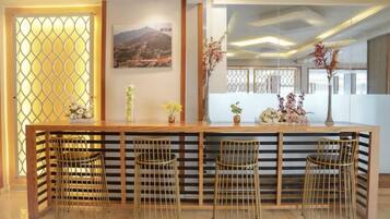 A reception area with a wooden counter, four metal chairs, and decorative plants.