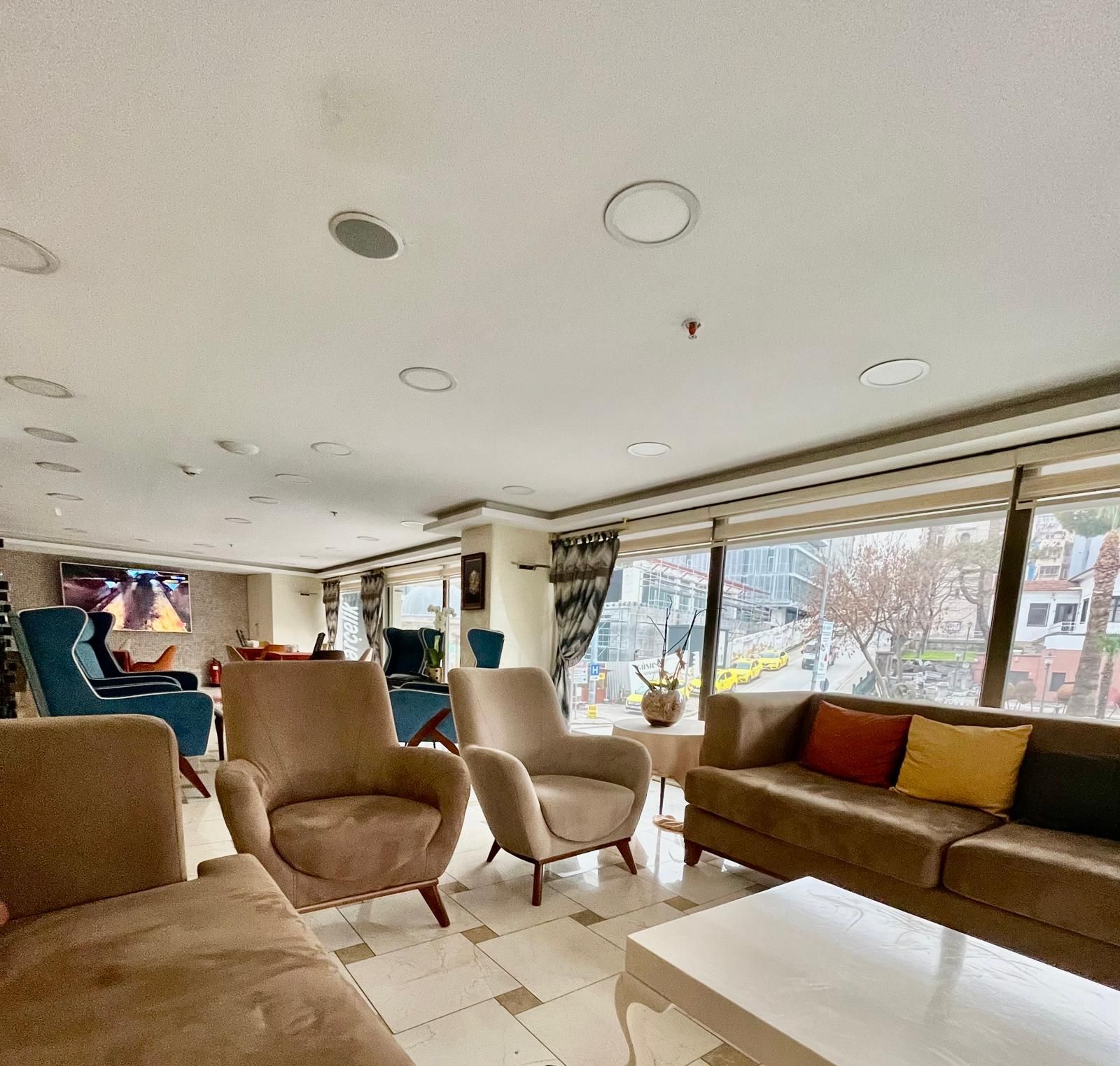 A spacious living area with modern furniture, a flat-screen TV, and large windows offering a view of the city.