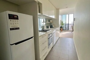 Una cuina moderna amb armaris blancs, forn integrat i nevera.