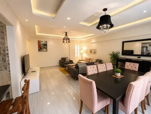 Una sala de estar moderna con comedor, televisión y candelabro.