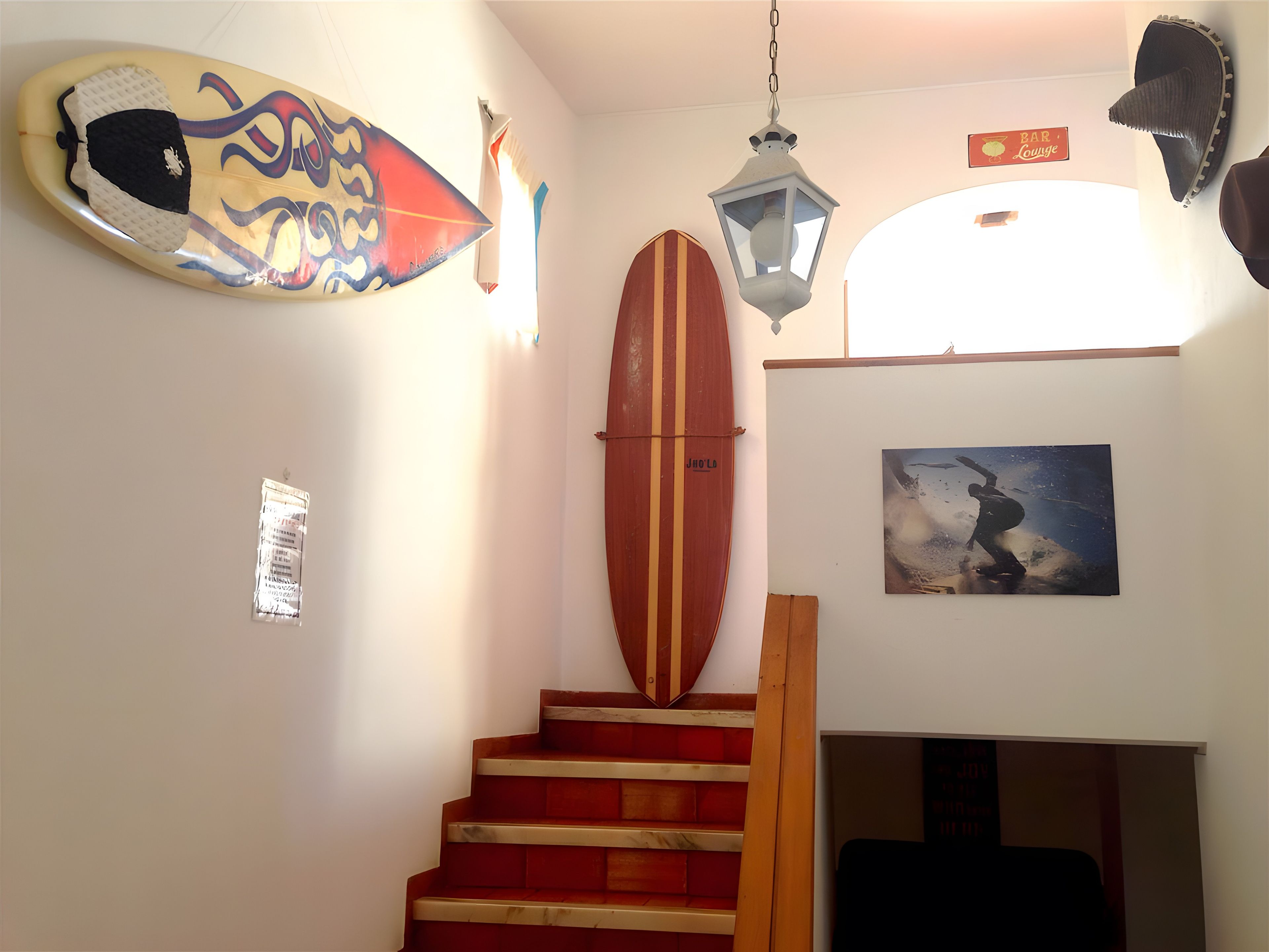 A staircase with a surfboard and a lantern.