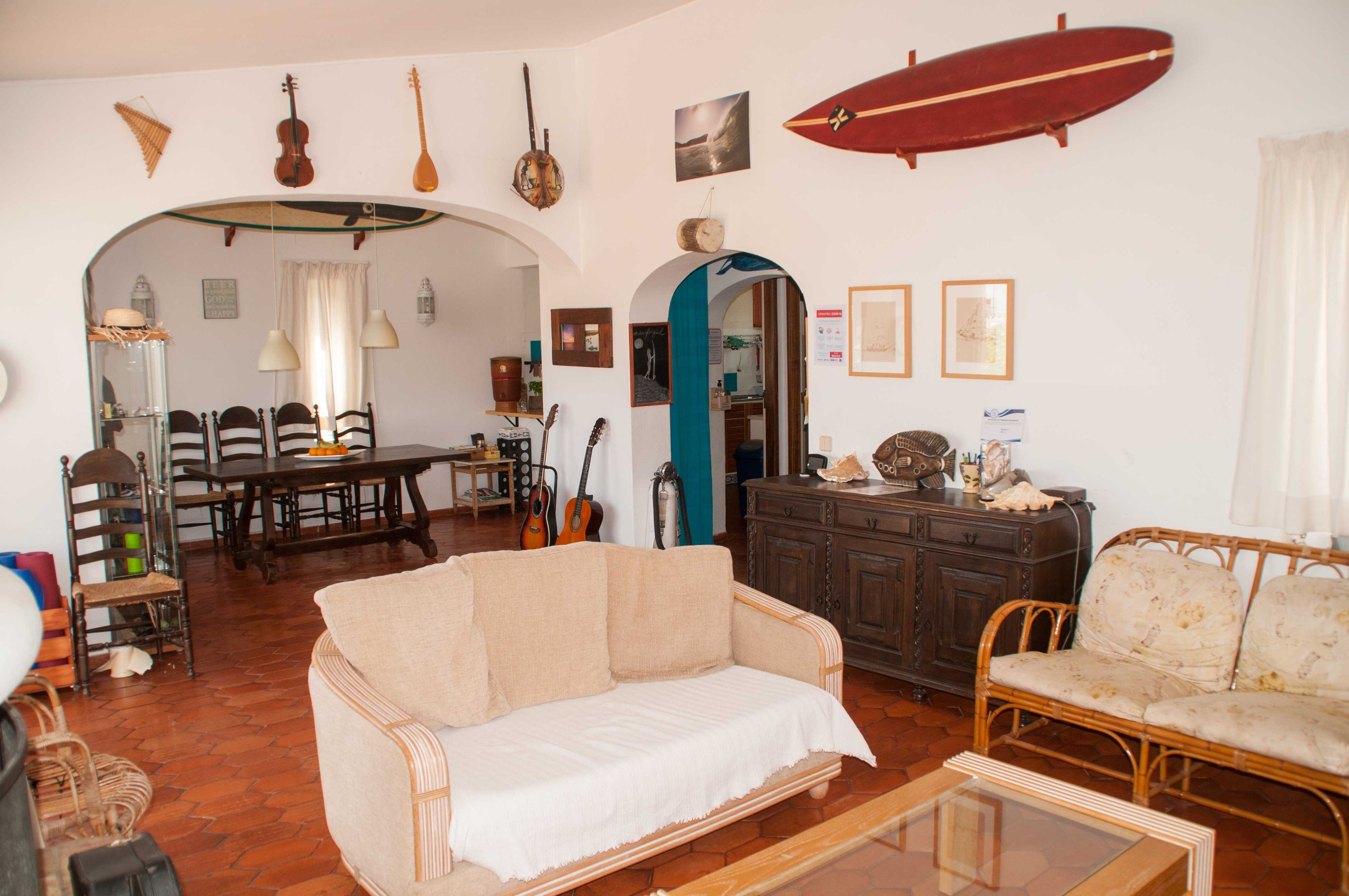 A cozy living room with a sofa, chairs, a dining table, and various musical instruments.