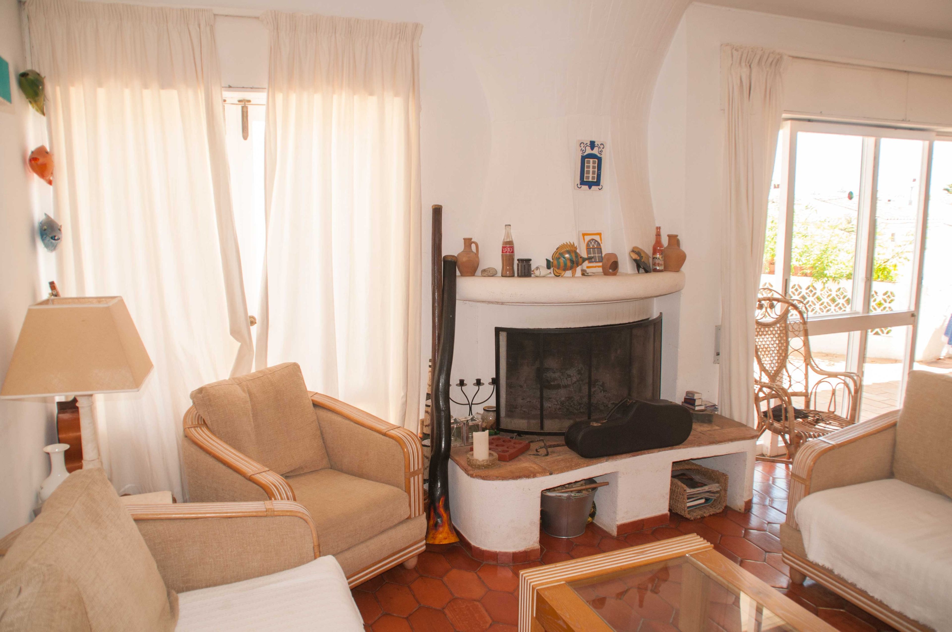 A living room with a fireplace, two armchairs, a lamp, and a window with curtains.