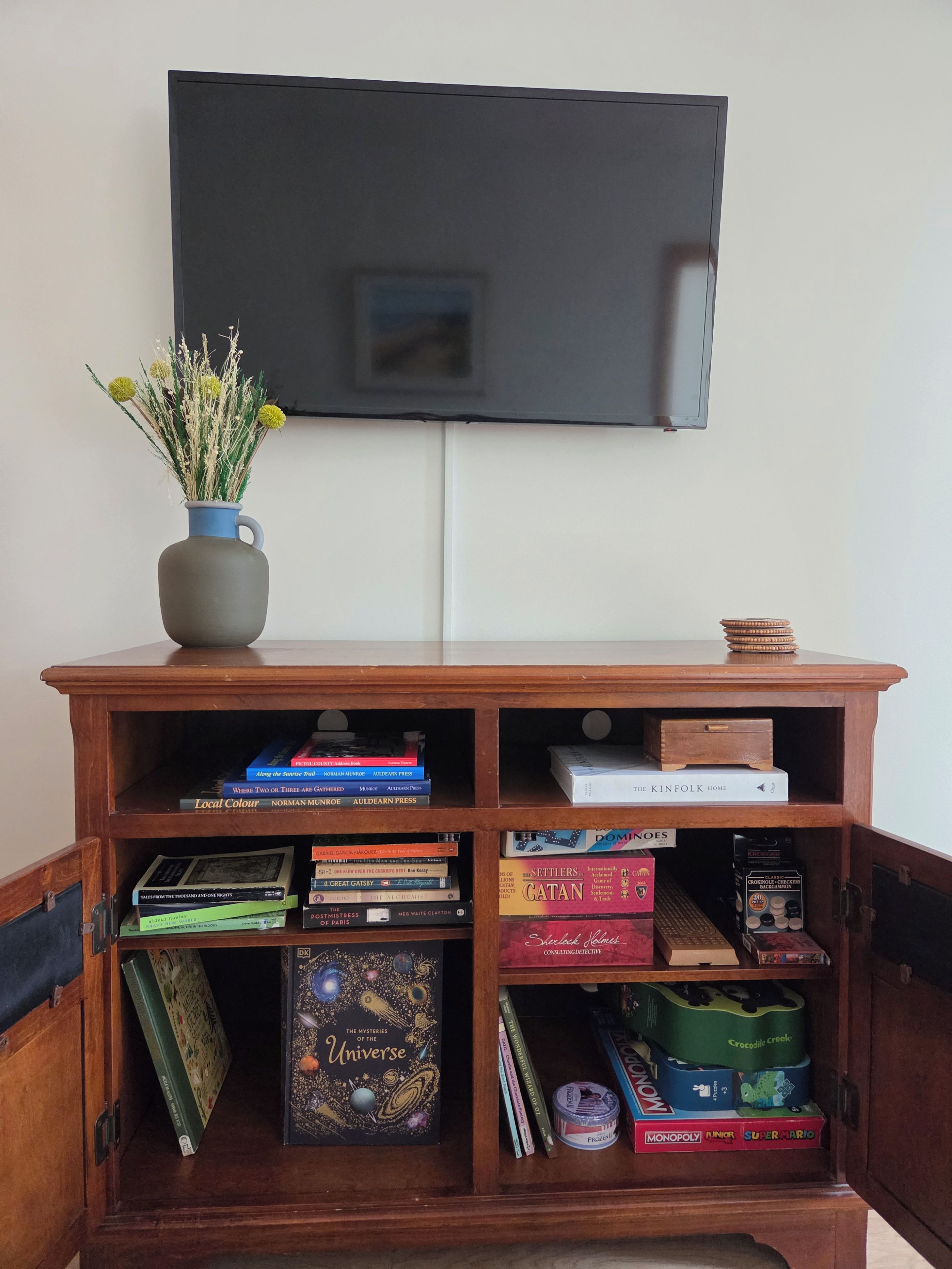 A wooden bookshelf with books and board games.