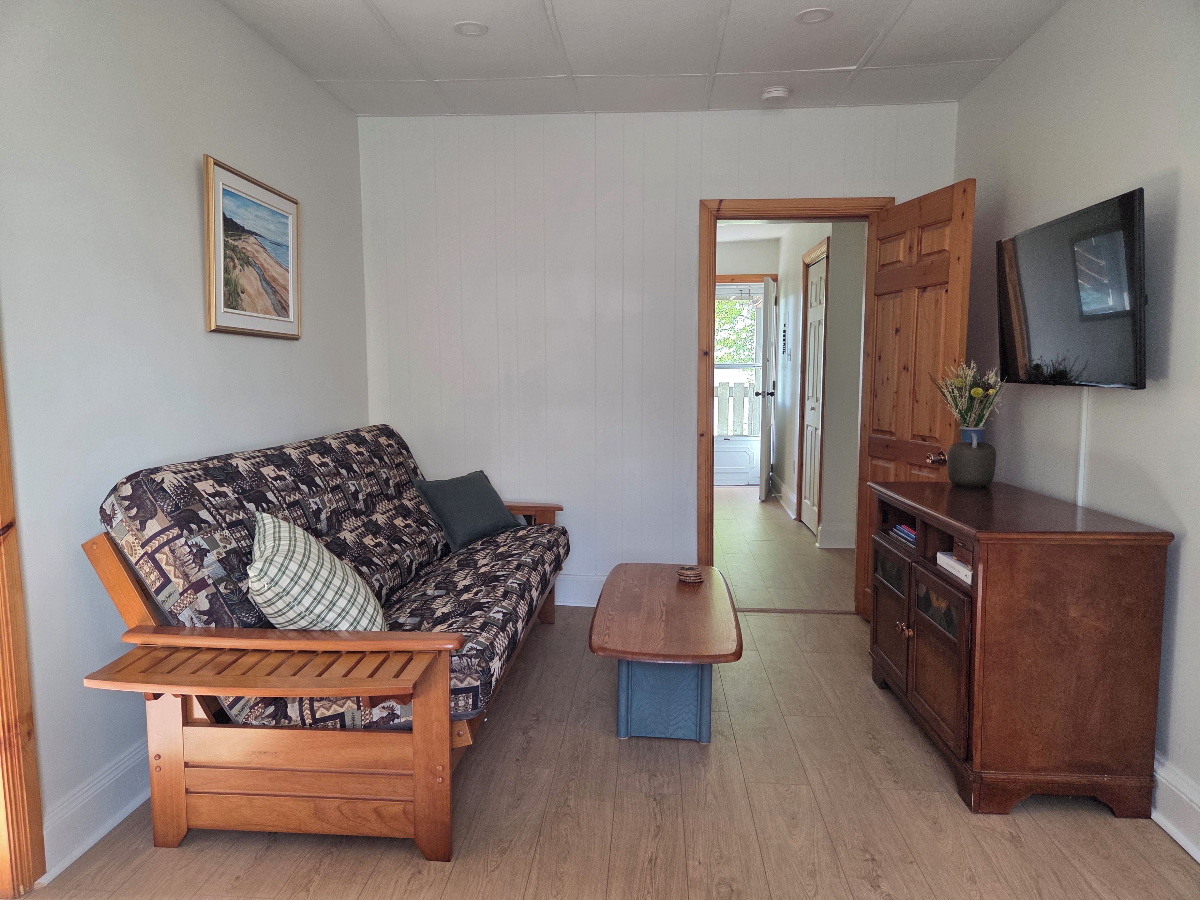 A living room with a sofa, a coffee table, a TV, and a wooden cabinet.