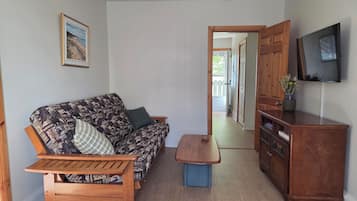 A living room with a sofa, a coffee table, a TV, and a wooden cabinet.