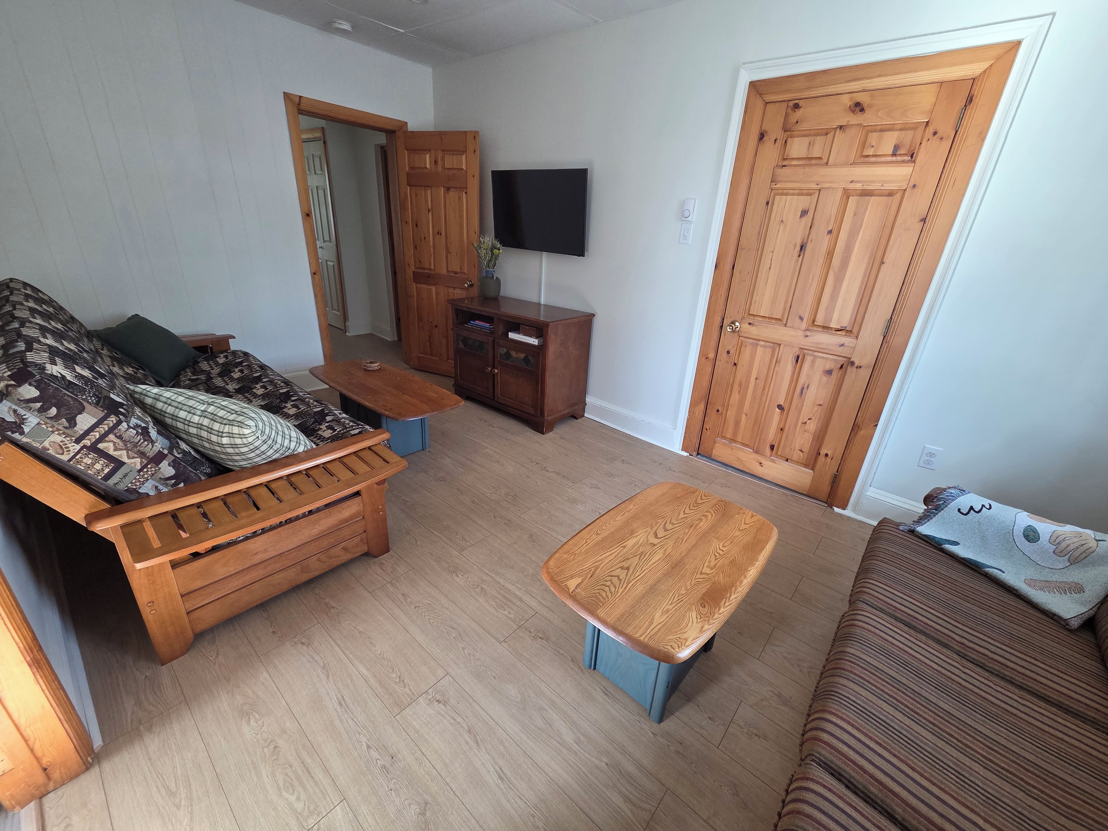 Un salon avec un canapé, une petite table, un téléviseur et des portes en bois.