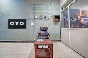 Una habitación con una silla de masajes, una mesa de madera y una pared con un cartel que dice 'OYO'.