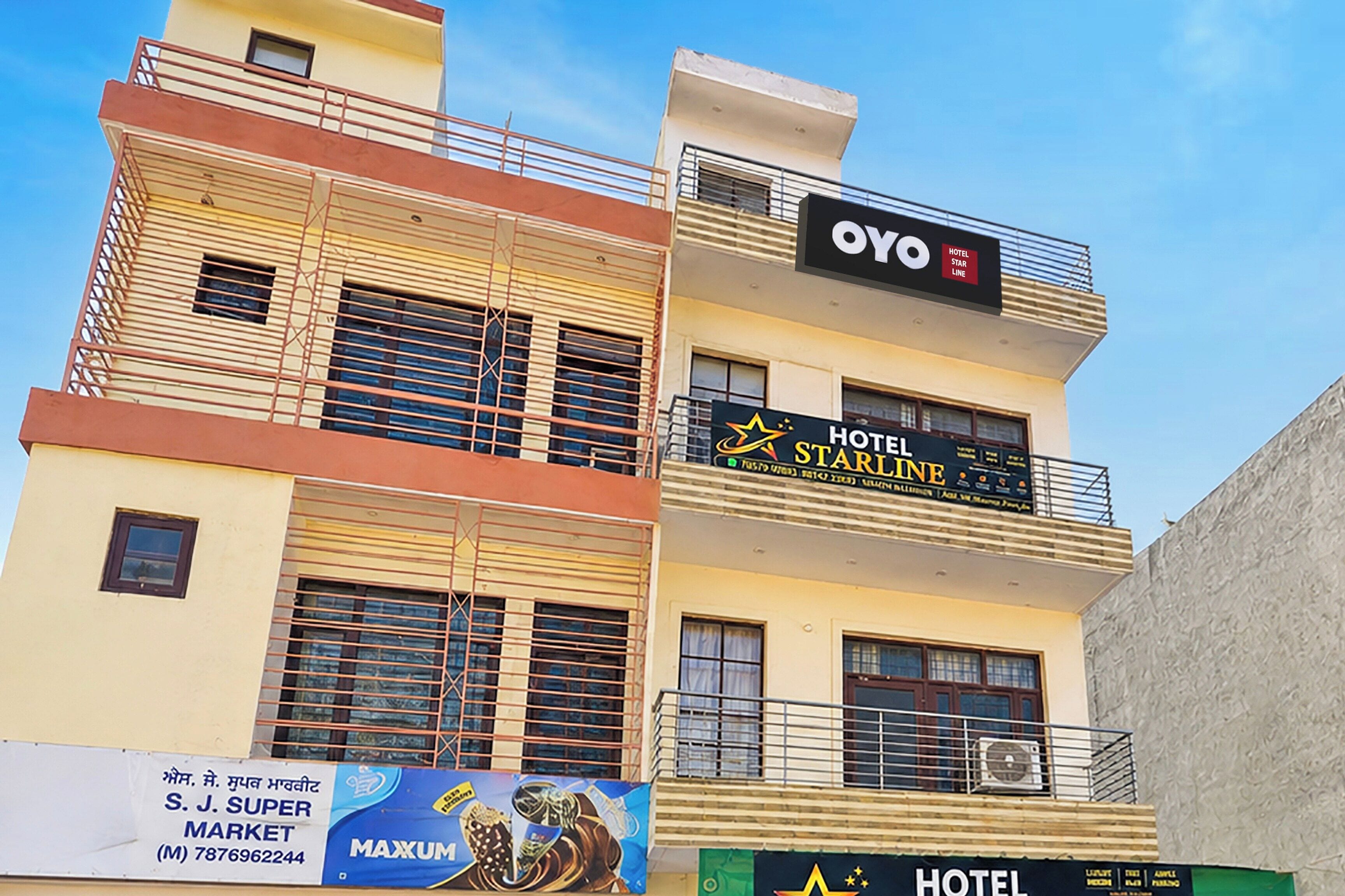 A multi-story building with a hotel named 'OYO STARLINE' on the top floor, featuring balconies and an air conditioning unit.