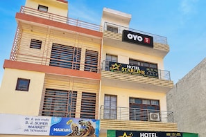 Un edificio de varios pisos con un hotel llamado 'OYO STARLINE' en el último piso, con balcones y un equipo de aire acondicionado.