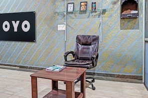A reception area with a leather chair, a wooden table, and a wall with a 'YO' sign. - Hotel O Starline (Zirakpur)
