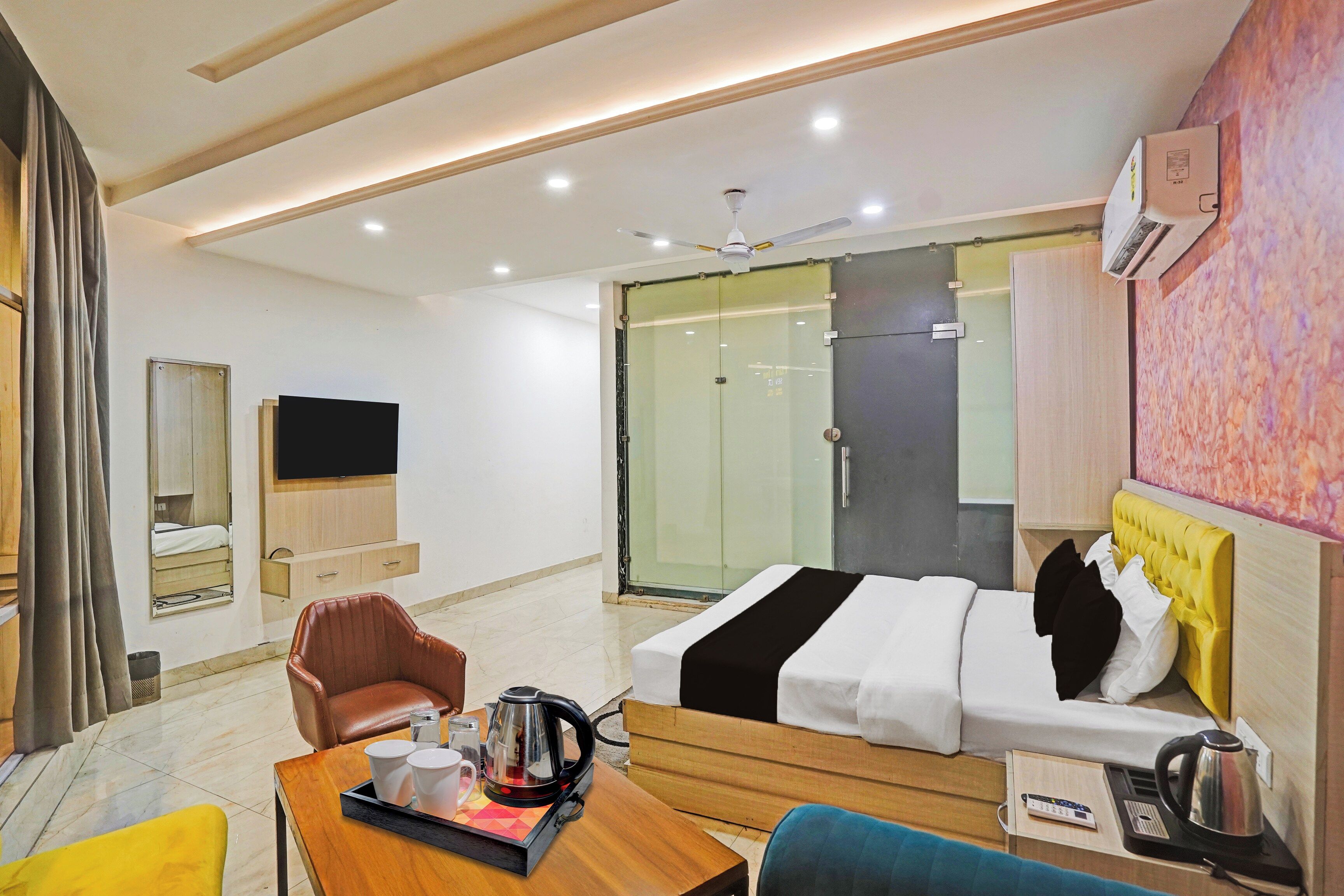 A hotel room with a bed, a seating area with a table, a television, and a sliding door leading to a bathroom.