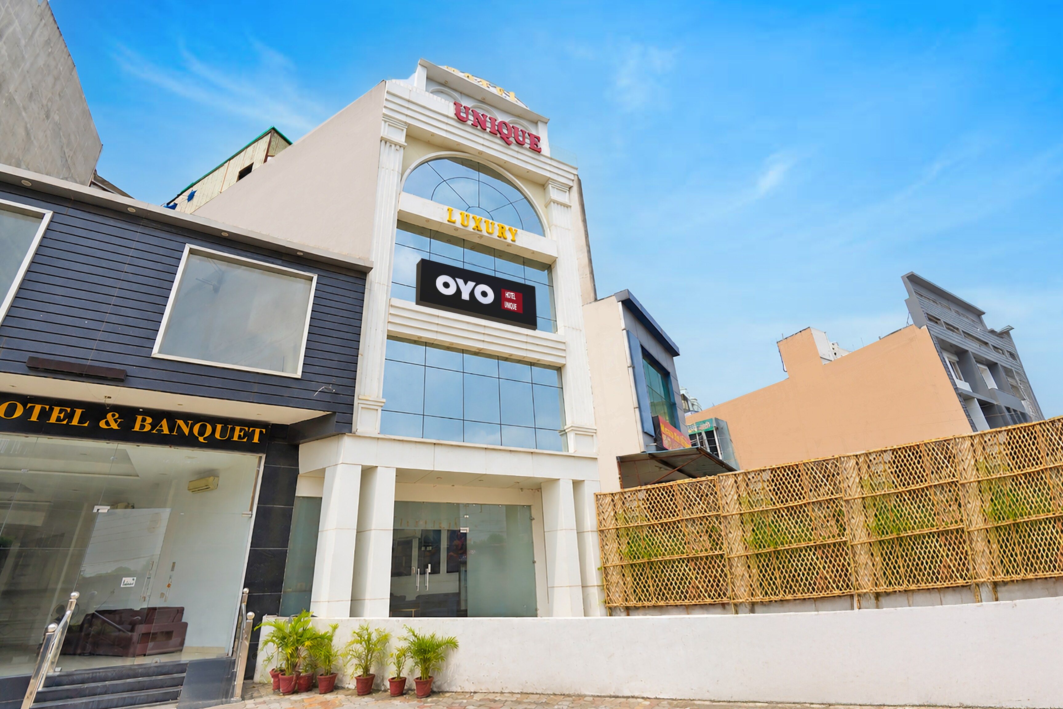 Un hotel con un cartel que indica 'OYO Hotel Unique' y 'Luxury' en la fachada.