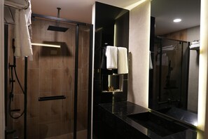 Un baño moderno con ducha de vidrio, encimera negra y un espejo grande.