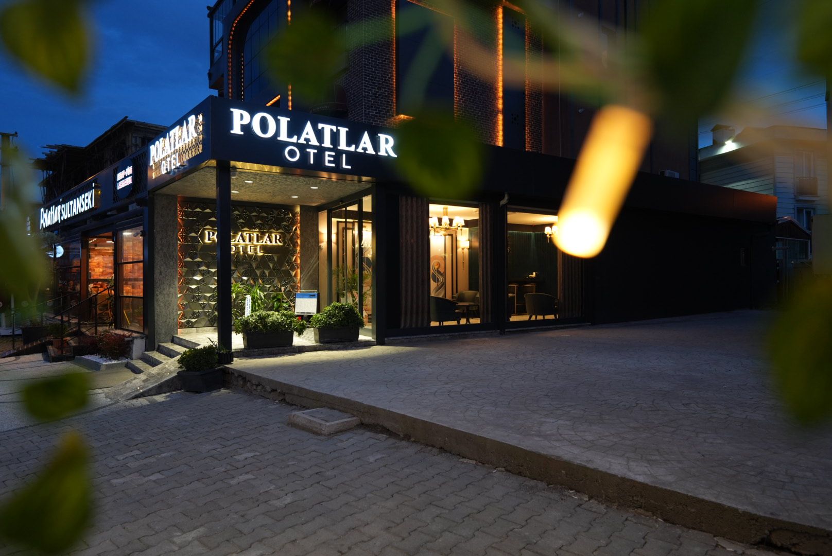 Entrada de un hotel con un cartel que dice 'POLATLAR HOTEL' y una escalera que lleva a la entrada.