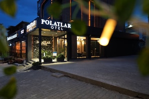 Entrada de un hotel con un cartel que dice 'POLATLAR HOTEL' y una escalera que lleva a la entrada.