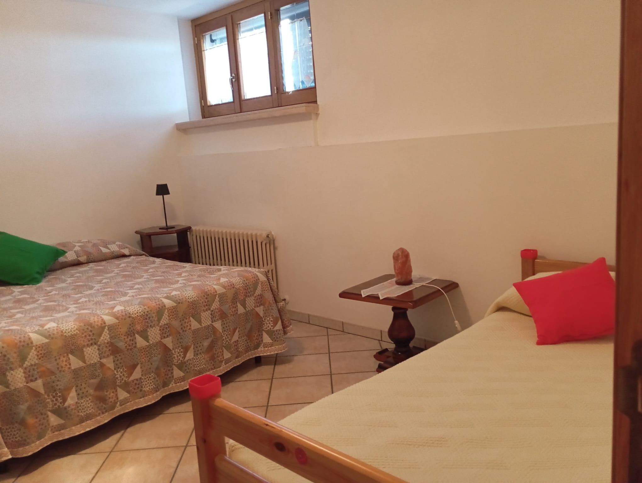 Ein Schlafzimmer mit einem Bett, einem Nachttisch, einer Lampe und einer Heizung.