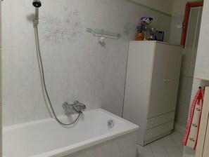 Un baño con bañera, ducha y un armario.
