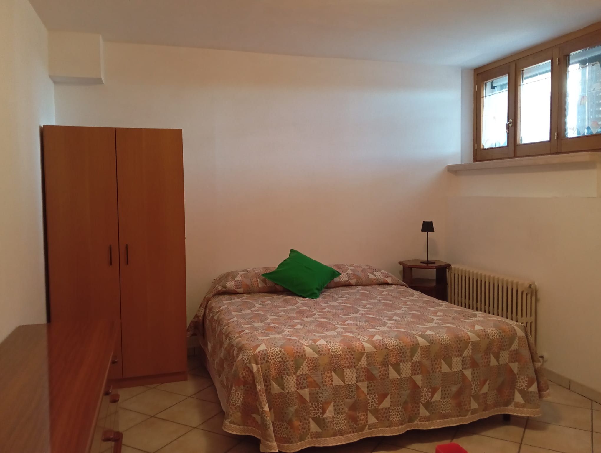 Une chambre à coucher avec un lit, une armoire, un radiateur et une fenêtre.