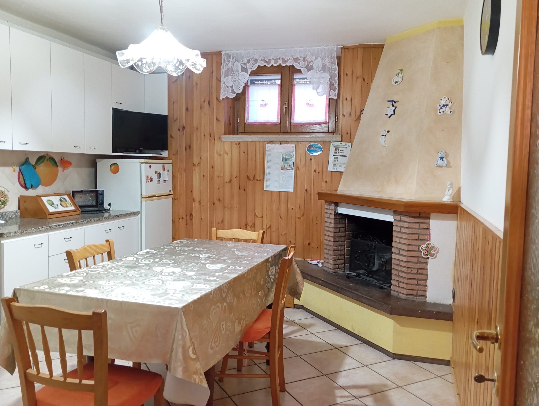 Eine Küche mit Esstisch, Stühlen, Fernseher, Kühlschrank und Kamin.