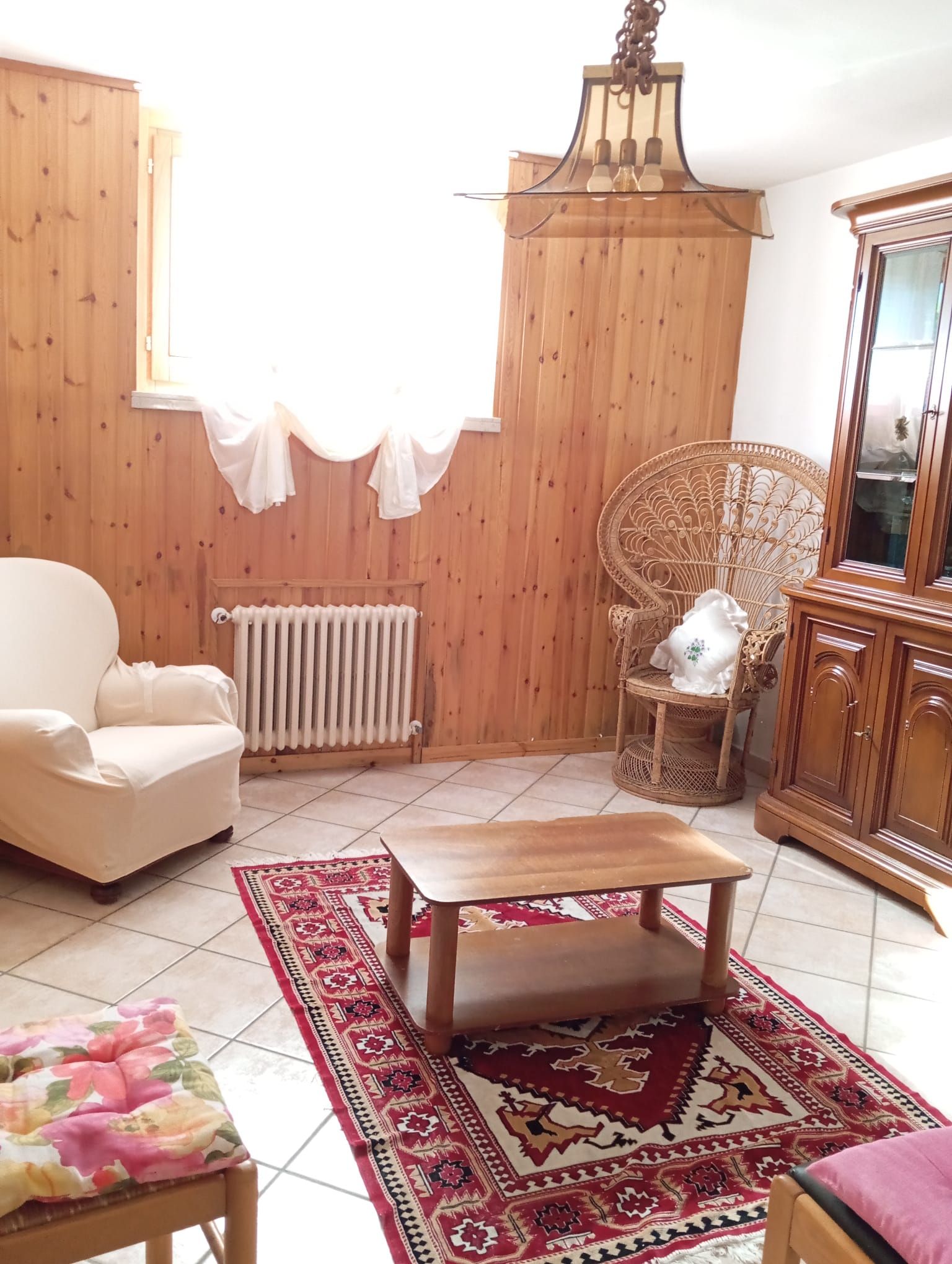Une pièce comprenant une chaise en bois, une table en bois, un radiateur et un tapis à motifs.